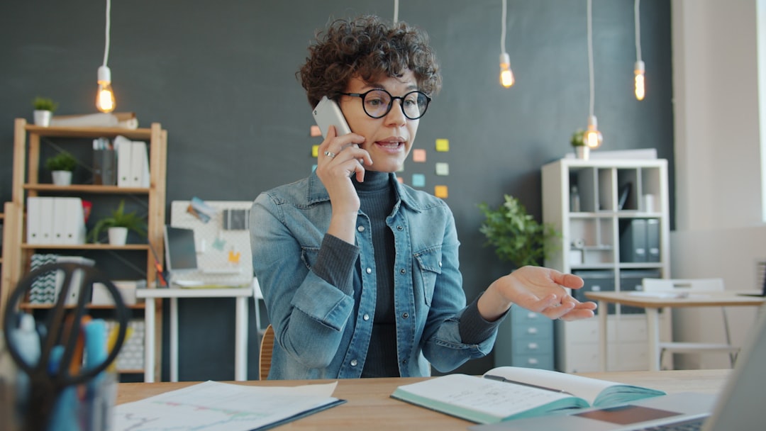 US small business owner reviewing AI receptionist dashboard on laptop showing voice call routing, chat handoff, and SMS response cost breakdown