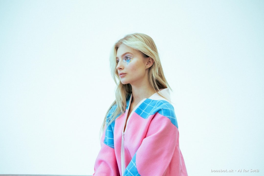 A young blonde woman in a pink and blue jacket.