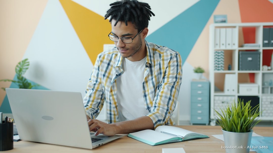 Man with glasses working on a laptop in an office.