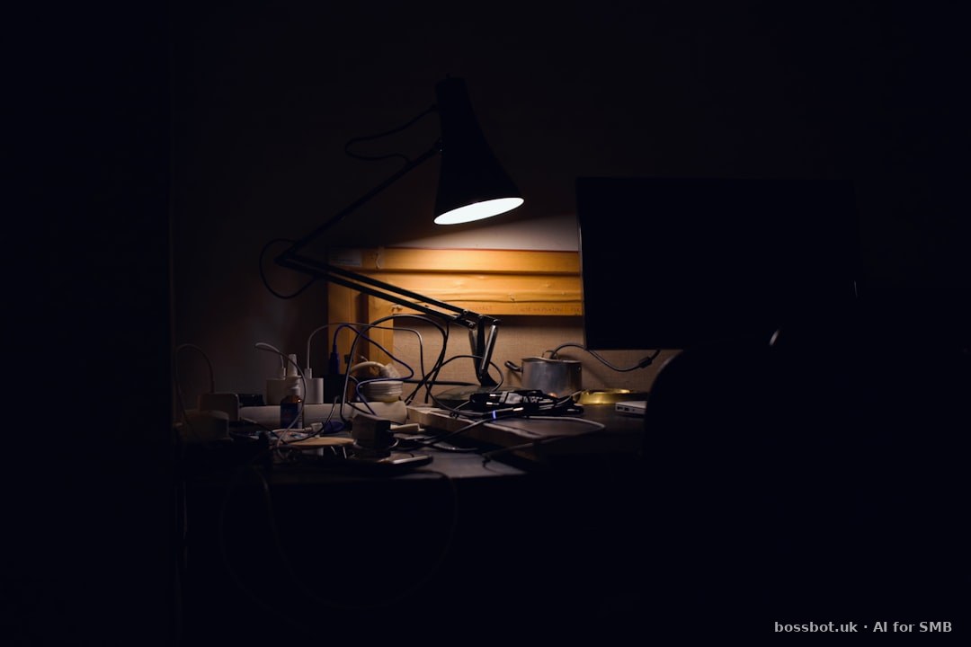 A dark room with a desk lamp and a computer