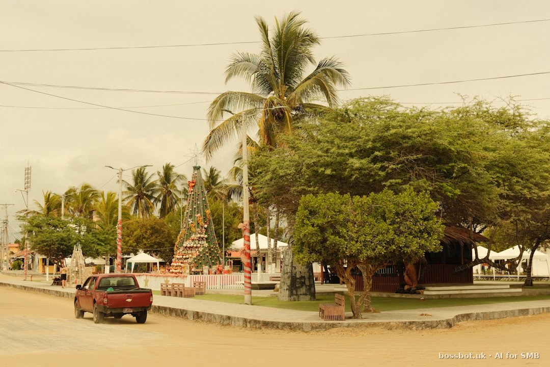 Red truck drives past a tropical town square.