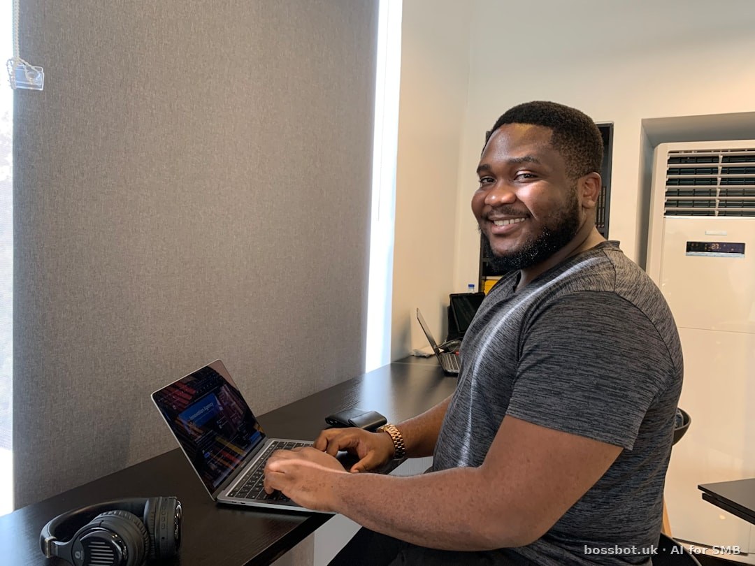 Person using laptop and mobile phone in office.