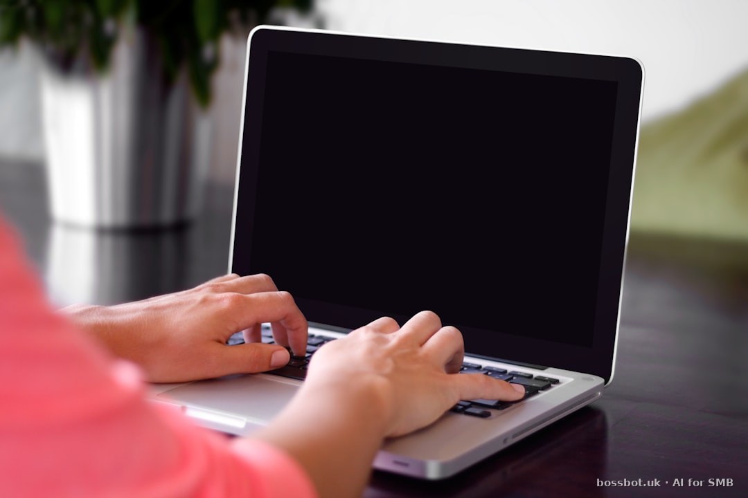 Person wearing pink shirt typing on gray laptop computer on desk