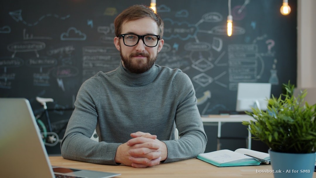 Man wearing glasses sits at a desk in office